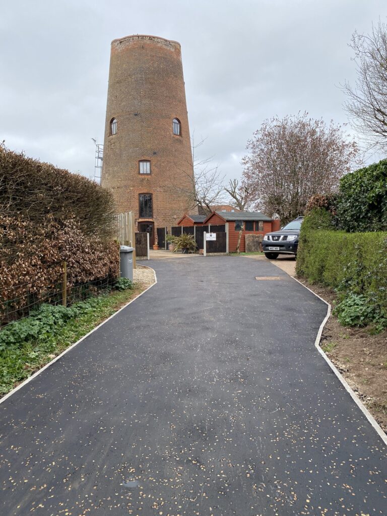 Ayslham windmill with a asphalt roadway with coloured chips and edging kerbs with a truck parked