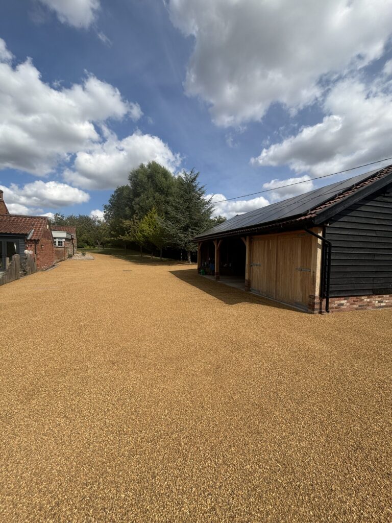 a large tar and chip driveway with a car port on a big countryside house in norfolk