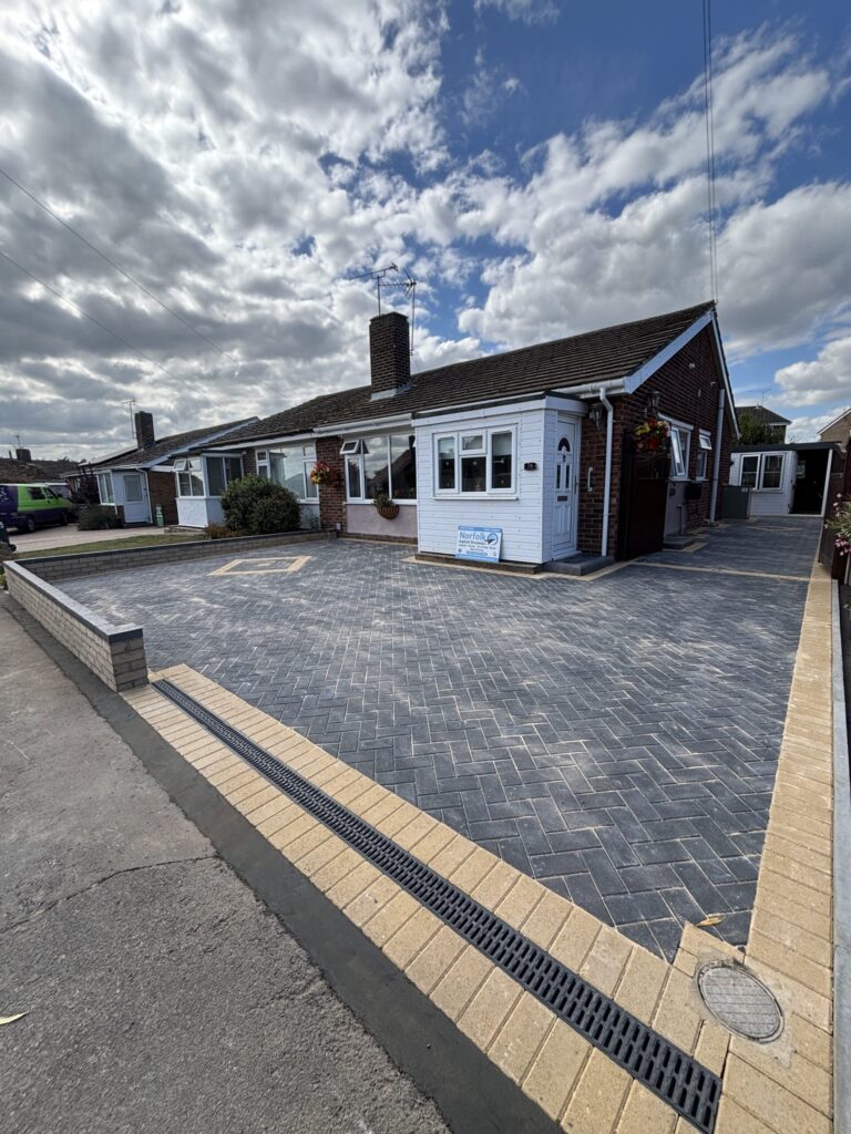 Buff soldier course edging bricks on a brick weave and block paved driveway with a charcoal centre block in a herringbone pattern